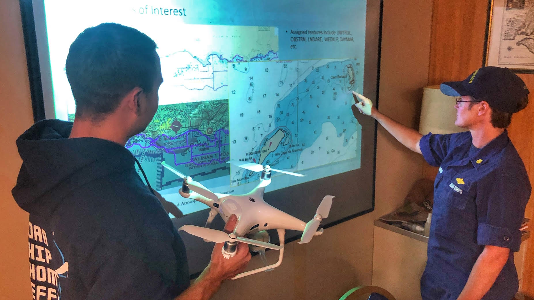 Lt. j.g. Matt Sharr holding the DJI Phantom 4 during a concept of operations brief for Lt. Cmdr. Meghan McGovern.