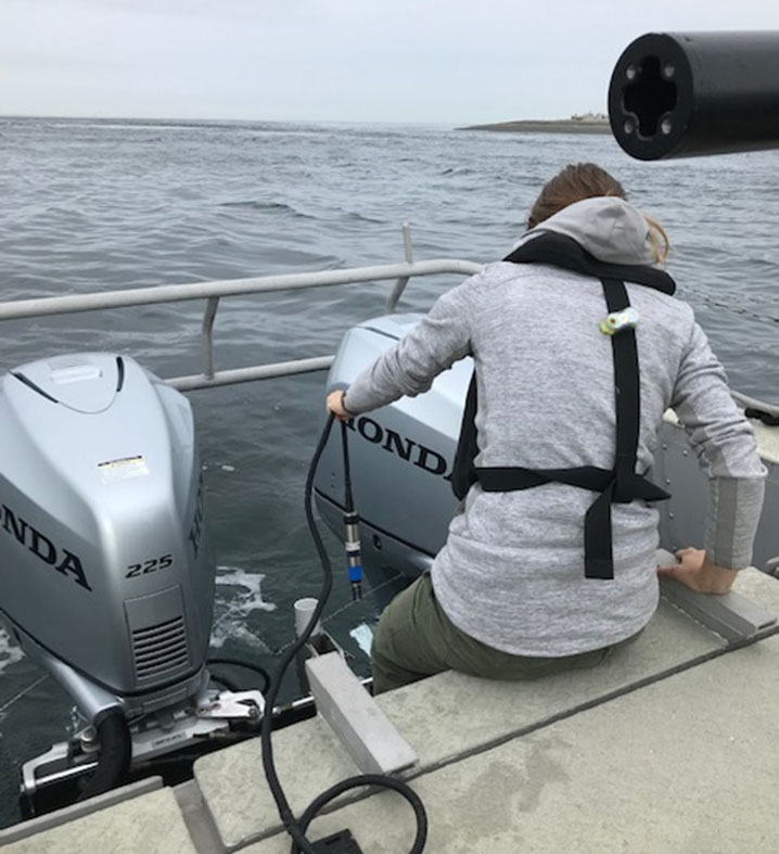 Intern Adrian Biesel prepares the boat for daily operations by deploying the surface sound speed sensor.